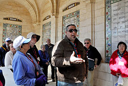 Tour guide Tony Azraq, a Palestinian Melkite Catholic, recites the Our Father in Hebrew at the Church of the Pater Noster on the Mount of Olives as the pilgrims listen on Feb. 10. (Photo by Natalie Hoefer)