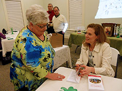 Elizabeth Hinson-Hasty prepares to sign a copy of her book, Dorothy Day for Armchair Theologians, for Phyllis Schickel. A Presbyterian minister and chair of the theology department at Bellarmine University in Louisville, Hinson-Hasty gave a talk on Day on March 12 as part of the annual Cardinal Ritter House Irish Coffee lecture series. (Photo by Patricia Happel Cornwell)