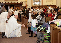 Archbishop Joseph W. Tobin receives a collection taken up during a March 17 Mass at St. Patrick Church in Indianapolis to celebrate the 150th anniversary of the founding of St. Patrick Parish. Bringing up the collection are, from left, Sheny and Jazmin Perez. Assisting Archbishop Tobin is Deacon Oscar Morales, left. (Submitted photos)
