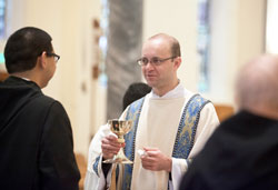 Transitional Deacon Michael Keucher serves as a Communion minister during a Mass on the Solemnity of the Immaculate Conception of the Blessed Virgin Mary on Dec. 8, 2014, at the Archabbey Church of Our Lady of Einsiedeln in St. Meinrad. He will be ordained a priest on June 6 at SS. Peter and Paul Cathedral in Indianapolis along with transitional deacons Adam Ahern and Andrew Syberg. (Photo courtesy of Saint Meinrad Archabbey)