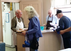 Bob Schafer, left, and Duane Miller, both members of St. Benedict Parish in Terre Haute, serve guests of the faith community’s soup kitchen on May 22. The charitable ministry has been in operation for around 25 years in the parish that is celebrating the 150th anniversary of its founding. (Submitted photo)