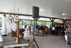 Father William Ehalt elevates the Eucharist during a May 31 Mass on the St. John the Evangelist campus of St. Catherine of Siena Parish in Decatur County. More than 300 members of the Batesville Deanery faith community took part in the Mass. Father Ehalt is St. Catherine’s pastor. (Photo by Sean Gallagher)