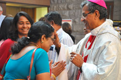 Bishop A. Jude Paulraj of the Diocese of Palayamkottai in India gives a blessing to Phelomina Fernando while her daughter, Leena Fernando, smiles in the narthex of St. Luke the Evangelist Church in Indianapolis on June 9. The bishop celebrated Mass there in thanksgiving for the parishioners’ donations to help build the cathedral in his diocese. Leena, a member at Our Lady of Mount Carmel Parish in Carmel, Ind., in the Lafayette Diocese, and her family lived at one time in the Palayamkottai Diocese. Her parents happened to be visiting her during the bishop’s stop at St. Luke. (Photo by Natalie Hoefer)