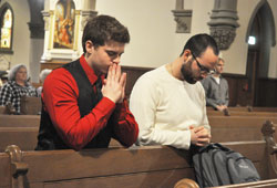 Nick Lesch, left, and Jake Firestine kneel in prayer during a Feb. 11, 2013, Mass at St. John the Evangelist Church in Indianapolis. Beginning in July, four parishes in downtown Indianapolis, as a result of the archdiocese’s Connected in the Spirit planning process, will coordinate their daily Mass schedules and offer more opportunities for the sacrament of reconciliation. (File photo by Sean Gallagher)