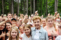 A sea of smiling children and youths at Camp Rancho Framasa in Brown County on June 17 give their thumbs-up signs of appreciation to Pat Cronin, the first counselor at the archdiocese’s Catholic Youth Organization summer camp when it opened in 1946. (Photo by John Shaughnessy)