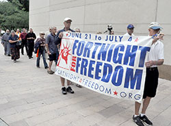 Frank Oliver, left, and Jim West carry a Fortnight for Freedom banner during a June 27 rosary procession from St. John the Evangelist Church to the grounds of the Indiana Statehouse in Indianapolis. The procession kicked off a rally for religious freedom attended by people from across the state. Oliver is a member of Our Lady of the Most Holy Rosary Parish in Indianapolis. West is a member of Our Lady of the Greenwood Parish in Greenwood. (Photo by Sean Gallagher)