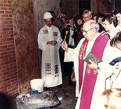 With members of St. Barnabas Parish looking on, Father John Sciarra blesses with holy water the cornerstone for the Indianapolis South Deanery’s church in 1985. For the first 20 years of its history, St. Barnabas, like many archdiocesan parishes founded during the baby-boom generation, had Masses celebrated in its school gymnasium. Father Sciarra, St. Barnabas’ founding pastor, retired in 1989. At left is Father Michael Fritsch, associate pastor of St. Barnabas at the time. (Submitted photo)