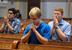 Archdiocesan seminarians Casimiro Samano-Reyes, left, Charlie Wessel and Nick McKinley kneel in prayer on Aug. 11 during a Mass at St. Mary Church in New Albany. The liturgy was part of a one-day pilgrimage that 23 archdiocesan seminarians took to the New Albany Deanery. (Photo by Sean Gallagher)
