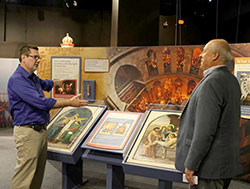 Chris Carron, left, director of collections at The Children’s Museum of Indianapolis, guides Ken Ogorek through the museum’s new “National Geographic Sacred Journeys” exhibit. Ogorek, archdiocesan director of catechesis and an exhibit advisor, helped secure two stations of the cross for a display on the Church of the Holy Sepulchre in Jerusalem. (Photo by Victoria Arthur)