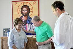 Paul Heerdink offers a prayer to God for Denise Sawyer as Scott Benningfield shares in the moment at St. John the Apostle Parish in Bloomington. The parish’s prayer ministry uses a prayer station, a prayer book and a group of “prayer warriors” to help people through the challenges of life. (Photo by John Shaughnessy) 