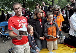 Sebastian, left, Ella, Angie and Benjamin Moster, members of St. Louis Parish in Batesville, kneel in prayer on Sept. 27 beside the Benjamin Franklin Parkway in Philadelphia during the closing Mass of the eighth World of Meeting of Families, attended by nearly 1 million worshippers. The Mosters participated in an archdiocesan pilgrimage to Philadelphia for the meeting. (Photo by Sean Gallagher)