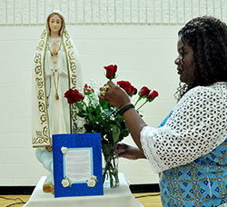 Dabrice Bartet, one of the coordinators of a 33 Days to Morning Glory Marian consecration group study at St. Monica Parish in Indianapolis, adjusts a bouquet of roses next to the statue of Mary used during the group’s consecration service on Sept. 12 in the parish’s gym. (Photos by Natalie Hoefer)