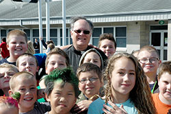 During recess at St. Vincent de Paul School in Bedford, children surround Father Rick Eldred, the pastor of that parish as well as St. Mary Parish in Mitchell, who has gained popularity with his outgoing personality and his “Popcorn with Padre” movie-hosting sessions at the school. (Photo by John Shaughnessy)