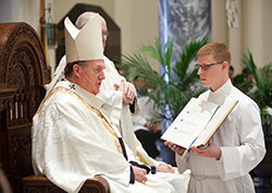 Archdiocesan seminarian Jeffrey Dufresne, right, assists at an April 11 deacon ordination Mass at the Archabbey Church of Our Lady of Einsiedeln in St. Meinrad. Archbishop Joseph W. Tobin, left, was the principal celebrant of the Mass. Dufresne, a member of St. Monica Parish in Indianapolis, currently receives priestly formation at Saint Meinrad Seminary and School of Theology in St. Meinrad. (Photo courtesy of Saint Meinrad Archabbey)