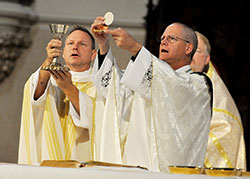 Father Rick Nagel, left, and Bishop Paul D. Etienne of Cheyenne, Wyo., elevate the Eucharist during an Oct. 31 Mass at St. John the Evangelist Church in Indianapolis. The Mass was part of the annual Indiana Catholic Men’s Conference. Father Nagel is pastor of St. John the Evangelist Parish. Bishop Etienne, formerly pastor of St. John, was a speaker at the conference. (Photo by Sean Gallagher)