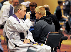 Father Anthony Rowland, left, associate pastor of Holy Spirit Parish in Fishers, Ind., in the Lafayette Diocese, gives absolution on Nov. 20 in the sacrament of penance to a NCYC attendee in a room set aside for the sacrament in the Indiana Convention Center in Indianapolis. (Photo by Sean Gallagher)