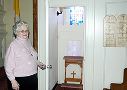 Carolyn Fenton stands outside a confessional at St. Joseph Church in Shelbyville. The sacrament of reconciliation has long had a special place in her life after a priest’s advice led her to the husband of her dreams, and to the realization that Jesus is present in the sacrament. (Photo by John Shaughnessy)