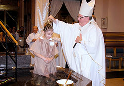 Archbishop Joseph W. Tobin baptizes Jocelyn Padilla-Palacios, a member of St. Monica Parish in Indianapolis, during the Easter Vigil Mass on March 26 at SS. Peter and Paul Cathedral in Indianapolis. Due to ongoing restoration from the September 2015 fire in their church narthex, members of St. Monica Parish celebrated their Easter Vigil with the members of the cathedral parish. (Submitted photo by Galo Catalan)