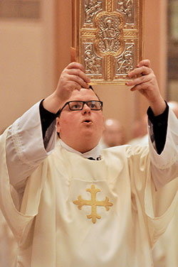 Transitional Deacon James Brockmeier prepares to proclaim the Gospel during the chrism Mass on March 22 at SS. Peter and Paul Cathedral in Indianapolis. (Photo by Sean Gallagher)