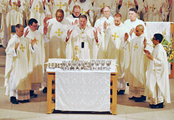 Archbishop Joseph W. Tobin prays the eucharistic prayer during a June 25 ordination Mass at SS. Peter and Paul Cathedral in Indianapolis. Joining him at the altar are, from left, Fathers Anthony Hollowell, James Brockmeier, Douglas Hunter, Kyle Rodden, Matthew Tucci and Nicolás Ajpacajá Tzoc, who were all ordained to the priesthood during the liturgy. Standing behind them are, from left, Deacon Stephen Hodges, Father Patrick Beidelman, Deacon Scott Bowman of the Colorado Springs, Colo., Diocese and Bishop James F. Checchio of the Metuchen, N.J., Diocese. (Photo by Sean Gallagher)
