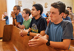 Kneeling in prayer during the June 16 Mass are John Paul Malinoski, left, Patrick Barron, Leo Ocampo—all members of Our Lady of the Most Holy Rosary Parish in Indianapolis—and Isaac Williams, a member of St. John the Apostle Parish in Bloomington. 
