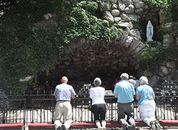 Pilgrims from central and southern Indiana kneel in prayer in front of the Our Lady of Lourdes grotto at the University of Notre Dame during an archdiocesan pilgrimage on July 19. (Photo by Natalie Hoefer)