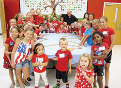 Children and Father J. Peter Gallagher are all smiles while surrounding a chocolate chip cookie rosary on July 1 during vacation Bible school at St. Lawrence Parish in Lawrenceburg, where Father Gallagher serves as pastor. The vacation Bible school program, which Father Jonathan Meyer helped develop, is an example of the authentic renewal of catechesis that has taken place in the Church since the end of the Second Vatican Council, and which has taken on new energy since the mid-1990s. (Submitted photo)