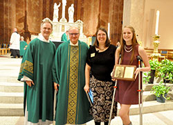 Roncalli High School sophomore Camille Woods, right, smiles as she stands with Deacon Michael Braun, left, Secretariat for Pastoral Ministries director; Msgr. William F. Stumpf, archdiocesan vicar general; and Rebecca Niemerg, director of the Office of Pro-Life and Family Life. Woods received the Our Lady of Guadalupe Respect Life Award at the end of the Respect Life Sunday Mass at SS. Peter and Paul Cathedral in Indianapolis on Oct. 2. (Photo by Natalie Hoefer)