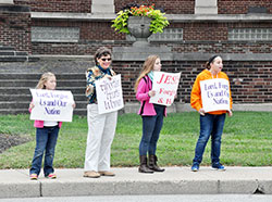 Heidi Hughey of St. Therese of the Infant Jesus (Little Flower Parish) in Indianapolis, left, Andrea Fleck of St. Roch Parish in Indianapolis, and Alice and Jackie Hughey, also of Little Flower Parish, hold signs in front of the Archbishop Edward T. O’Meara Catholic Center during the Life Chain event in Indianapolis on Oct. 2. (Photo by Natalie Hoefer)