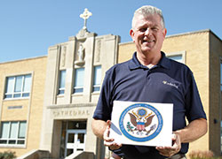 Dave Worland, principal of Cathedral High School in Indianapolis, poses outside with a sign recognizing the school’s designation as a 2016 National Blue Ribbon School—the only high school in Indiana to receive that recognition this year. (Submitted photo)