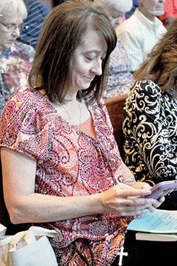 Agenia Hurrle, a member of St. Barnabas Parish in Indianapolis, uses a smart phone to share a “mercy pledge” on Oct. 8 during the Marian Jubilee at St. Bartholomew Church in Columbus. (Photo by Sean Gallagher)