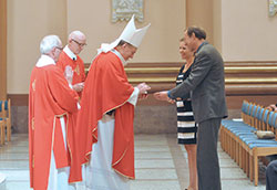 Cardinal-designate Joseph W. Tobin receives offertory gifts from Mary Jo and Andreas Sashegyi, members of SS. Peter and Paul Cathedral Parish, during the Miter Society Mass on Oct. 18 at SS. Peter and Paul Cathedral in Indianapolis. Deacons Steven Gretencord, left, and Patrick Bower assist Cardinal-designate Tobin. (Photos by Natalie Hoefer)