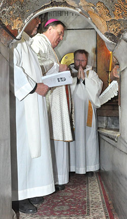 Archbishop Joseph W. Tobin, center, celebrates Mass at the site venerated as Christ’s tomb in the Church of the Holy Sepulcher in Old City Jerusalem on Feb. 13, 2015. He is assisted by Father Robert Mazzola, left, and Father Joseph Newton, right. (File photo by Natalie Hoefer)