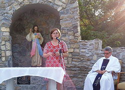 Mary Rose Carlow, a member of Prince of Peace Parish in Madison, speaks on Oct. 4 about the Divine Mercy image during a dedication ceremony for the parish’s new grotto, an effort she envisioned, raised funds for and coordinated. Prince of Peace pastor Father Christopher Craig sits at right. (Submitted photo by Cathy Fox)