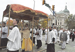 Father Rick Nagel, pastor of St. John the Evangelist Parish in Indianapolis, holds a monstrance while leading a eucharistic procession on Nov. 19 past the Indiana Statehouse during the 10th annual Indiana Catholic Men’s Conference. (Photo by Sean Gallagher) 