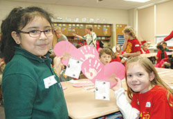 St. Philip Neri first-grader Suzet Cruz, left, and St. Jude first-grader Grace Denney proudly show the cut-out hearts they decorated with their hand prints on Feb. 1, the day when students from both Indianapolis schools came together to share their faith and learn from each other. (Photo by John Shaughnessy)