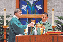 Father David Bu Nyar, right, celebrates Mass with the assistance of Deacon Thomas Horn, St. Mark the Evangelist Parish’s pastoral associate, at St. Mark the Evangelist Church on Feb. 11. Father Bu Nyar was invited by then-Archbishop Joseph W. Tobin to come from Myanmar to serve the refugees of that country now worshipping at St. Mark and St. Pius X parishes in Indianapolis. (Photo by Natalie Hoefer)	