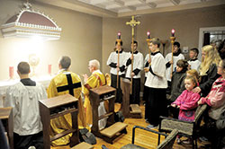 Father Jonathan Meyer, pastor of All Saints Parish in Dearborn County, second from left, and Deacon Robert Decker, joins several altar servers and other parishioners in praying before the Blessed Sacrament on March 1 in the Batesville Deanery faith community’s new perpetual adoration chapel on its St. John the Baptist campus in Dover. (Photo by Sean Gallagher)
