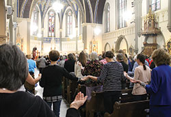 Women hold hands during the Our Father in a packed St. John the Evangelist Church for Mass during the Indiana Catholic Women’s Conference in Indianapolis. (Photo by Victoria Arthur)