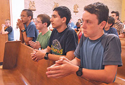 Kneeling in prayer during a Mass that was a part of Bishop Bruté Days at Bishop Simon Bruté College Seminary in Indianapolis in June 2016 are John Paul Malinoski, left, Patrick Barron, Leo Ocampo—all members of Our Lady of the Most Holy Rosary Parish in Indianapolis—and Isaac Williams, a member of St. John the Apostle Parish in Bloomington. (File photo by Sean Gallagher)