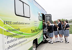 Middle school students of SS. Francis and Clare of Assisi School in Greenwood step onto the Great Lakes Gabriel Project’s mobile ultrasound RV unit, which lists its services on the side. (Photo by Natalie Hoefer)