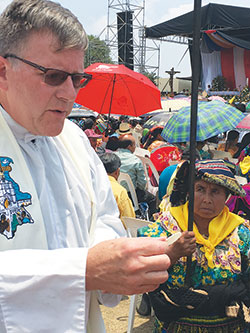 Father Michael O’Mara, pastor of St. Gabriel the Archangel Parish in Indianapolis, distributes Communion during the April 27 Mass celebrating the 50th anniversary of the Quiche diocese in Guatemala.