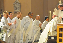 Fathers Anthony Hollowell, left, James Brockmeier, Kyle Rodden, Douglas Hunter, Matthew Tucci and Nicholas Ajpacaja Tzoc kneel together during the Mass when they were ordained into the priesthood in the archdiocese on June 25, 2016. Their first year as priests have led to memorable moments in their ministry. (Photo by John Shaughnessy)