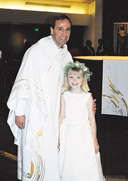 Then-Father Charles Thompson, left, pastor of Holy Trinity Parish in Louisville, poses with Christine Kelly after she received her first Communion in the spring of 2003. (Photo courtesy Joan Kelly)