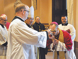 During the Solemn Evening Prayer service at SS. Peter and Paul Cathedral in Indianapolis on July 27, Archbishop Charles C. Thompson reverences a crucifix held by Father Patrick Beidelman, rector of the cathedral, as Msgr. William F. Stumpf, left, apostolic nuncio to the United States Archbishop Christophe Pierre, Benedictine Archabbot Kurt Stasiak of Saint Meinrad Archabbey in St. Meinrad, and Father Jerry Byrd look on. (Photo by Sean Gallagher)