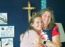 The shared experience of facing a diagnosis of cancer has brought Kristen Battiato, left, and Cindy Wallander close during the past year. Here, they share a hug in a classroom at St. Joan of Arc School in Indianapolis, where Wallander teaches. (Photo by John Shaughnessy)