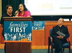 Maira Bordonabe, a member of St. Gabriel the Archangel Parish in Indianapolis and a married mother of two, shares her story of being taken for deportation as Archbishop Charles C. Thompson listens. Speaking in English before a crowd at an IndyCAN “families first” budget rally in Indianapolis on Aug. 30, Bordonabe’s story was translated into Spanish by Yuri Rodriguez, left. (Photo by Natalie Hoefer)