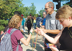 Deacon Russell Woodard, parish life coordinator of Holy Trinity Parish in Edinburgh, and Kelley Snoddy (in blue shirt) of St. Bartholomew Parish in Columbus pass out rosaries and prayer cards to a group of young people as they share their Catholic faith near a farmer’s market in Columbus on Aug. 26. (Photo by John Shaughnessy)