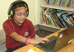 Second-grade student Makenzie Yates enjoys using an adaptive computer program at Holy Angels School in Indianapolis, a program that identifies the academic level of each student and uses fun concepts to help them progress individually and as a group. It’s part of the school’s comprehensive “blended-learning” program that has become a model in the archdiocese. (Photo by John Shaughnessy) 