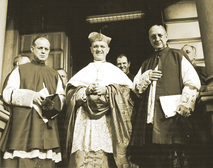 On Jan. 16, 1961, Archbishop Joseph E. Ritter of St. Louis, who had served as the bishop and later archbishop of Indianapolis from 1933 to 1946, was created a cardinal by Pope John XXIII. In celebration, the Archdiocese of Indianapolis hosted “Cardinal Ritter Day” on Feb. 12, 1961. This event included a religious reception at the cathedral, a dinner for priests at the Indianapolis Athletic Club, and a public reception in the Cathedral High School gymnasium (now the Catholic Center assembly hall). In this photo, Cardinal Ritter, along with archdiocesan priests Msgr. James Hickey, left, and Msgr. James Jansen, pose on the steps of the cathedral rectory before heading to the religious reception.